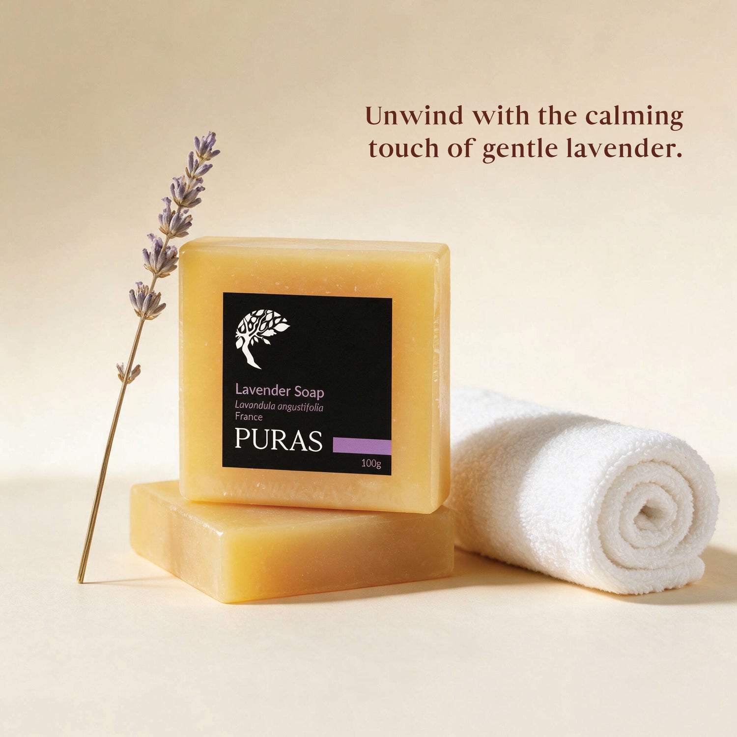A bar of PURAS lavender soap stands on another bar, with a rolled white towel and a lavender sprig beside it on a warm beige background. Text reads: 'Unwind with the calming touch of gentle lavender.