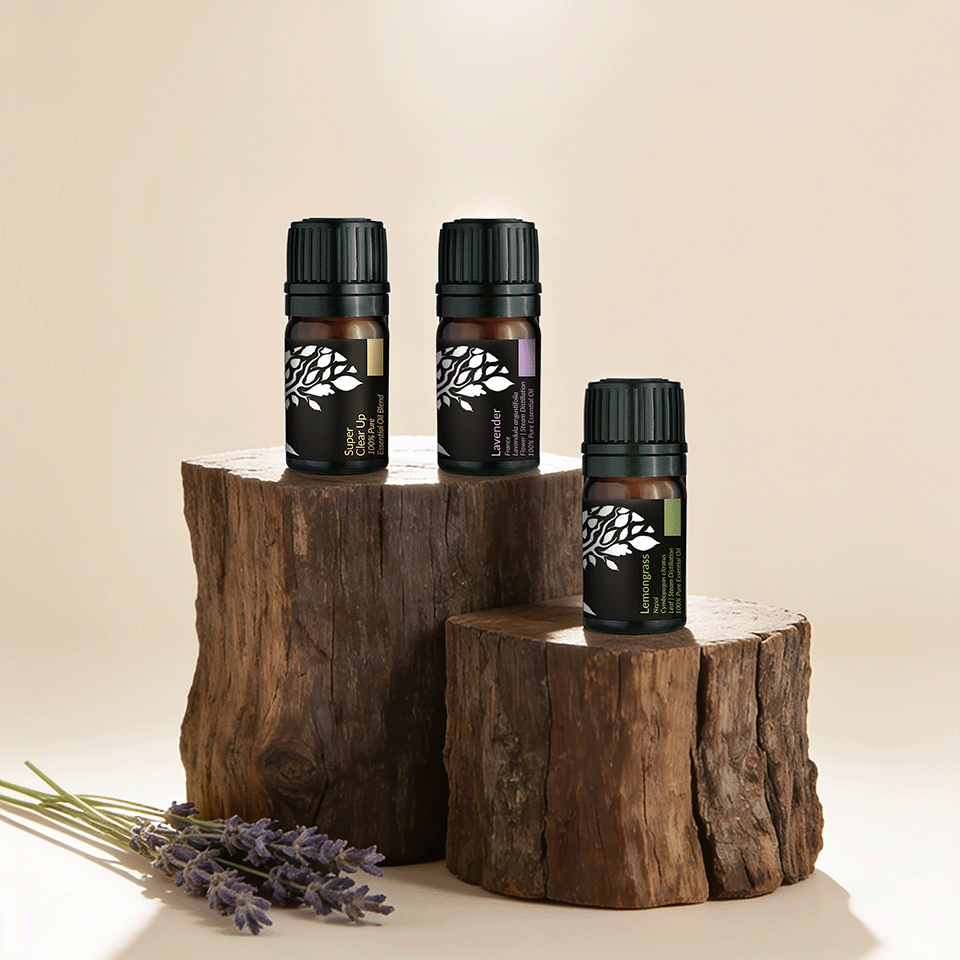 Three essential oil bottles with black caps and dark labels are displayed on rustic wooden log pedestals against a warm beige background, with lavender sprigs in the foreground.