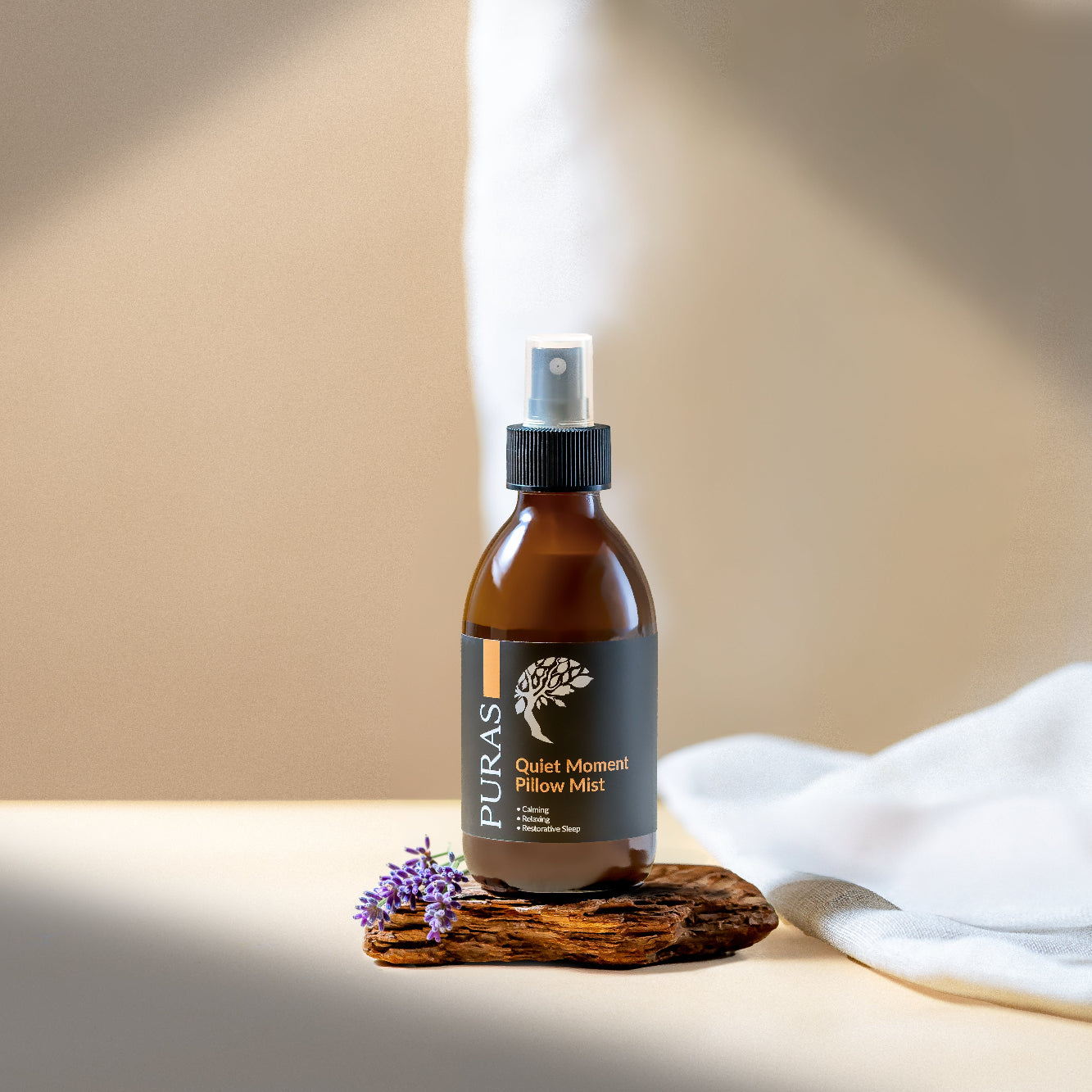 Puras Quiet Moment pillow mist spray with lavender flowers, against a neutral background.