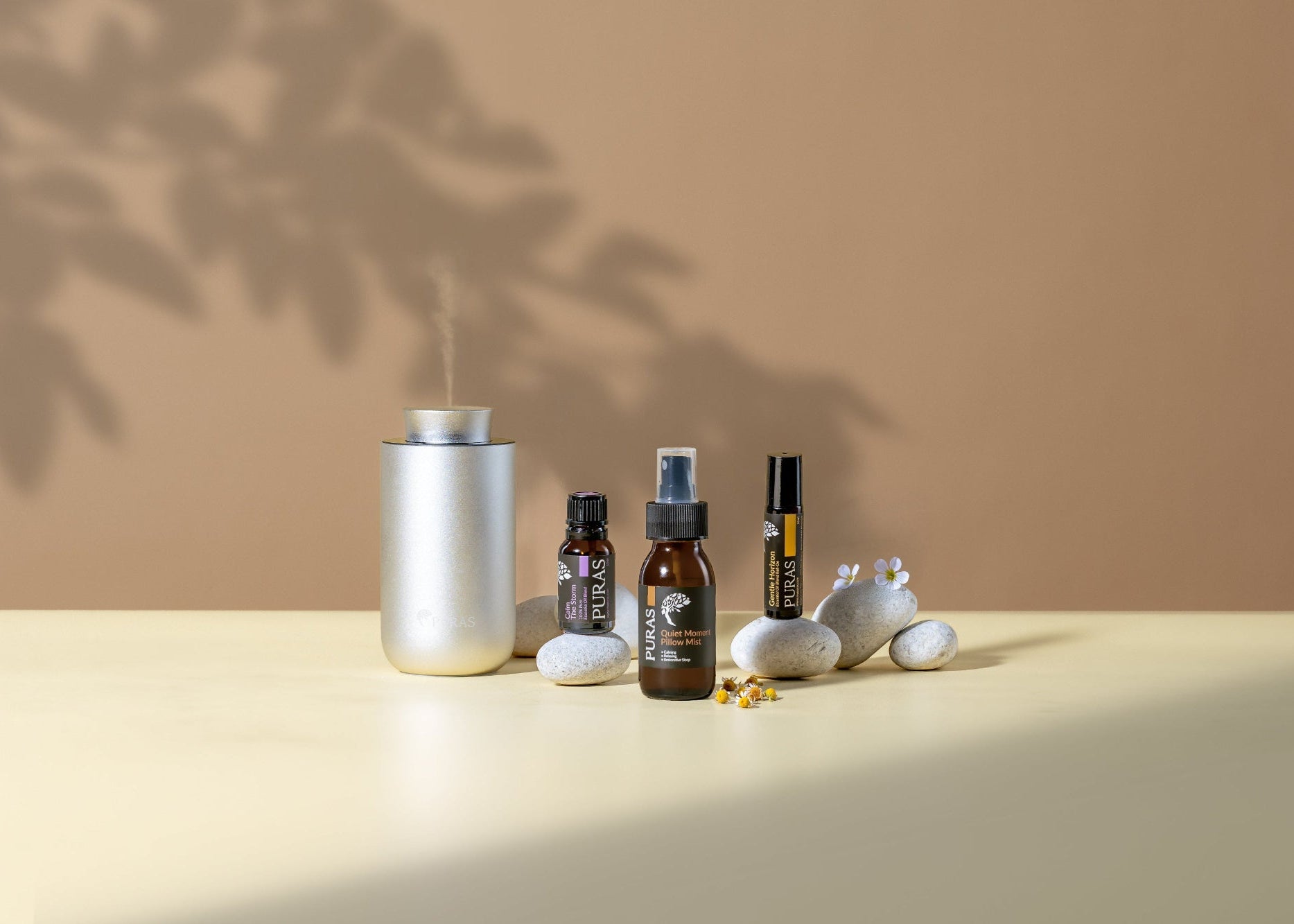 Collection of essential oil bottles and a diffuser on a beige surface with a neutral background