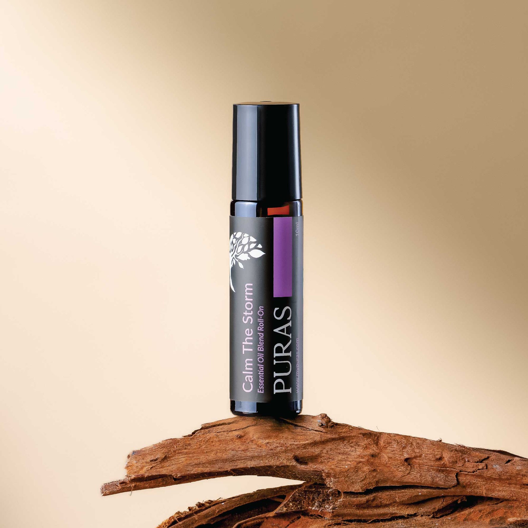 Puras "Calm The Storm" essential oil roller bottle on a wooden surface with a beige background