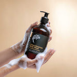 Hand holding a bottle of Citrus Geranium Body Wash with a beige background