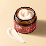 Jar of 'Dragon's Blood' antioxidant sleeping mask opened with texture on a beige background