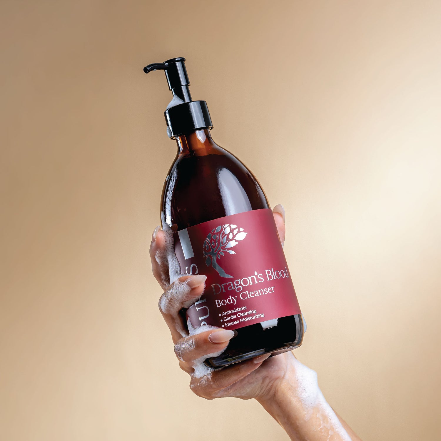 Hand holding a bottle of 'Dragon's Blood' body cleanser with a beige background