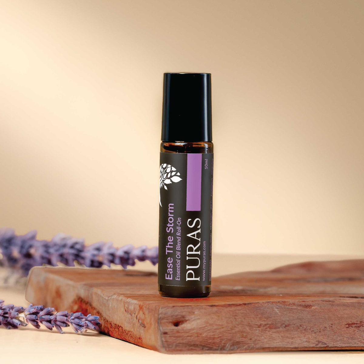 Puras "Ease The Storm" essential oil bottle with lavender flowers on a wooden surface