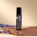 Puras "Ease The Storm" essential oil bottle with lavender flowers on a wooden surface