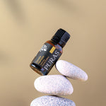 Puras essential oil bottle balanced on stones with a beige background