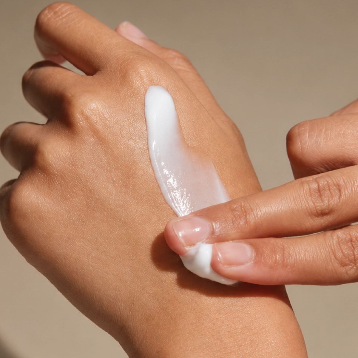 Hand cream being gently applied to the back of the hand.