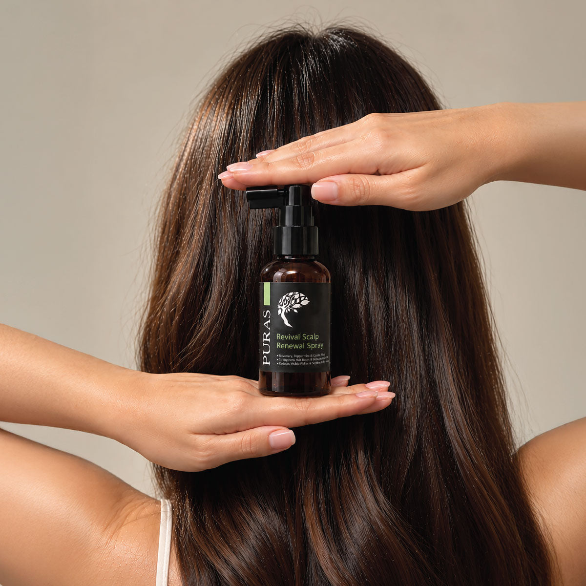 Woman holding PURAS Revival Scalp Renewal Spray against her long, healthy-looking hair.