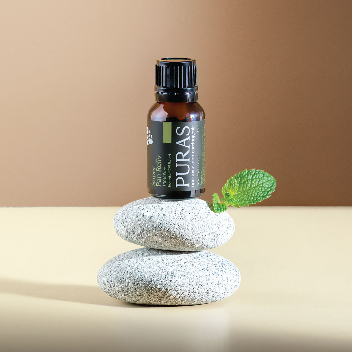 Puras essential oil bottle on stacked stones with a green leaf against a beige background
